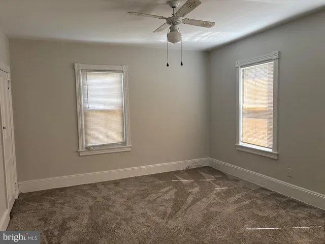an empty room with windows and fan