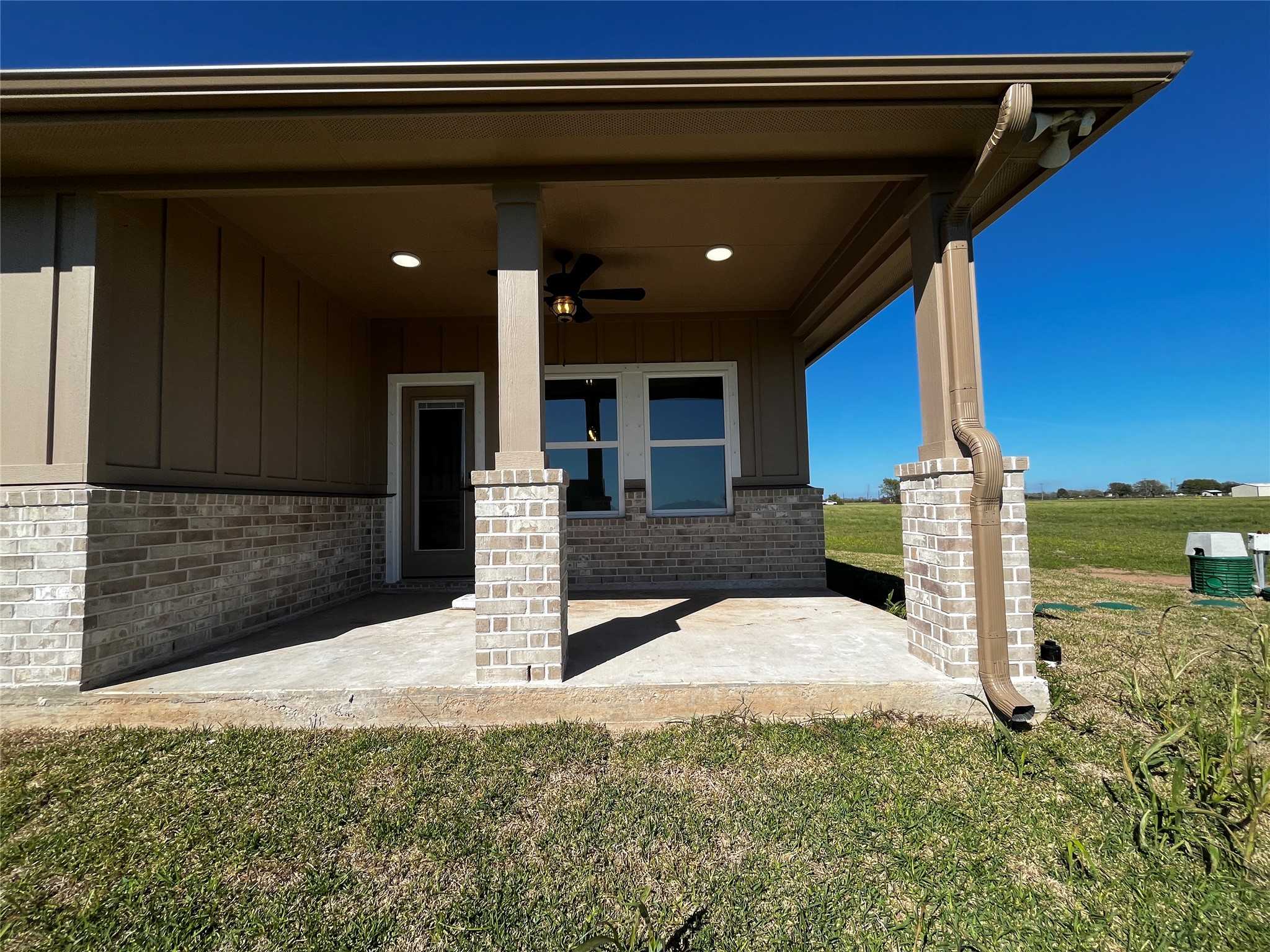 471 Buffalo Trail Angleton, TX 77515 - Photo 31 of 35 Porch showcases a charming covered patio with brick accents and columns. It features a ceiling fan and lighting, providing a cozy outdoor space. The area overlooks a spacious green lawn, perfect for relaxation or entertaining.