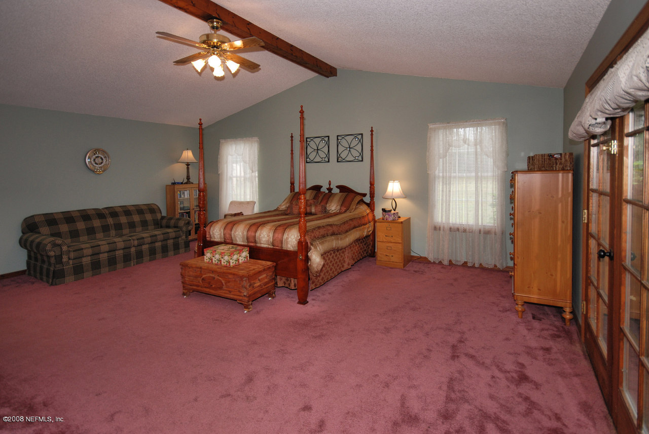 15591 Flounder Road Jacksonville, FL 32226 - Photo 9 of 12 a spacious bedroom with a bed and a chandelier