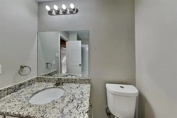 a bathroom with a granite countertop toilet a sink and a mirror