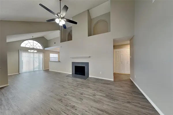 a view of an empty room with a fireplace and a chandelier fan