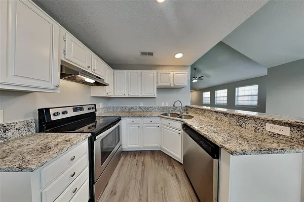 a kitchen with stainless steel appliances granite countertop a sink stove and cabinets