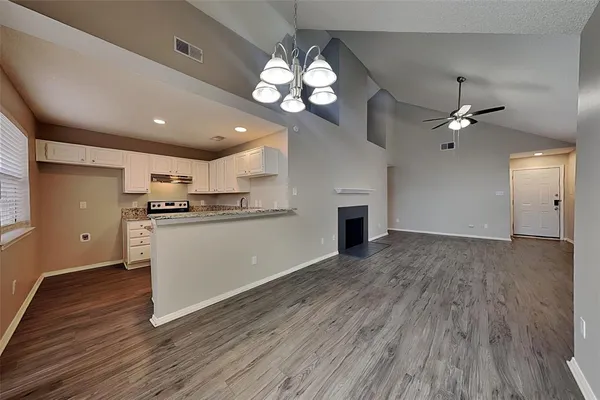 a view of a kitchen with an empty room and wooden floor