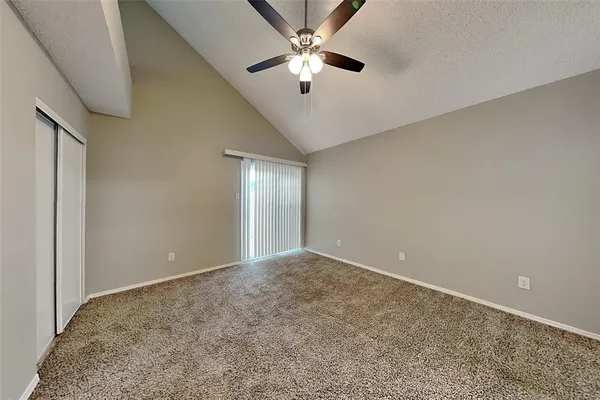 a view of an empty room and chandelier fan