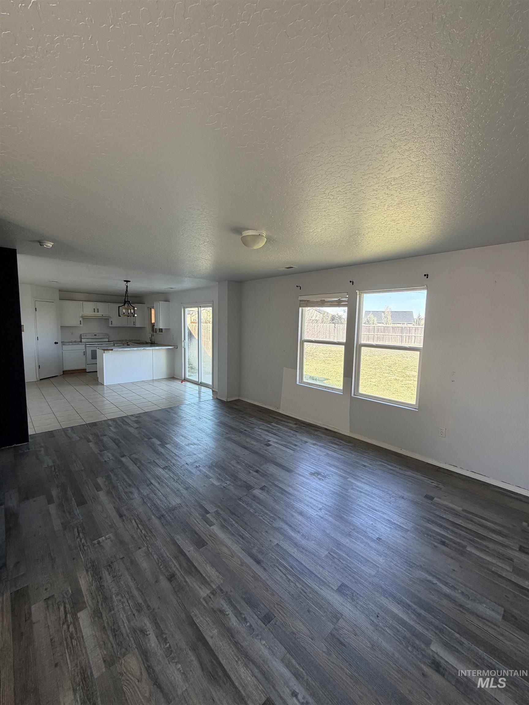 205 Middlepark Way Caldwell, ID 83605 - Photo 5 of 18 Unfurnished living room with a textured ceiling and dark wood finished floors