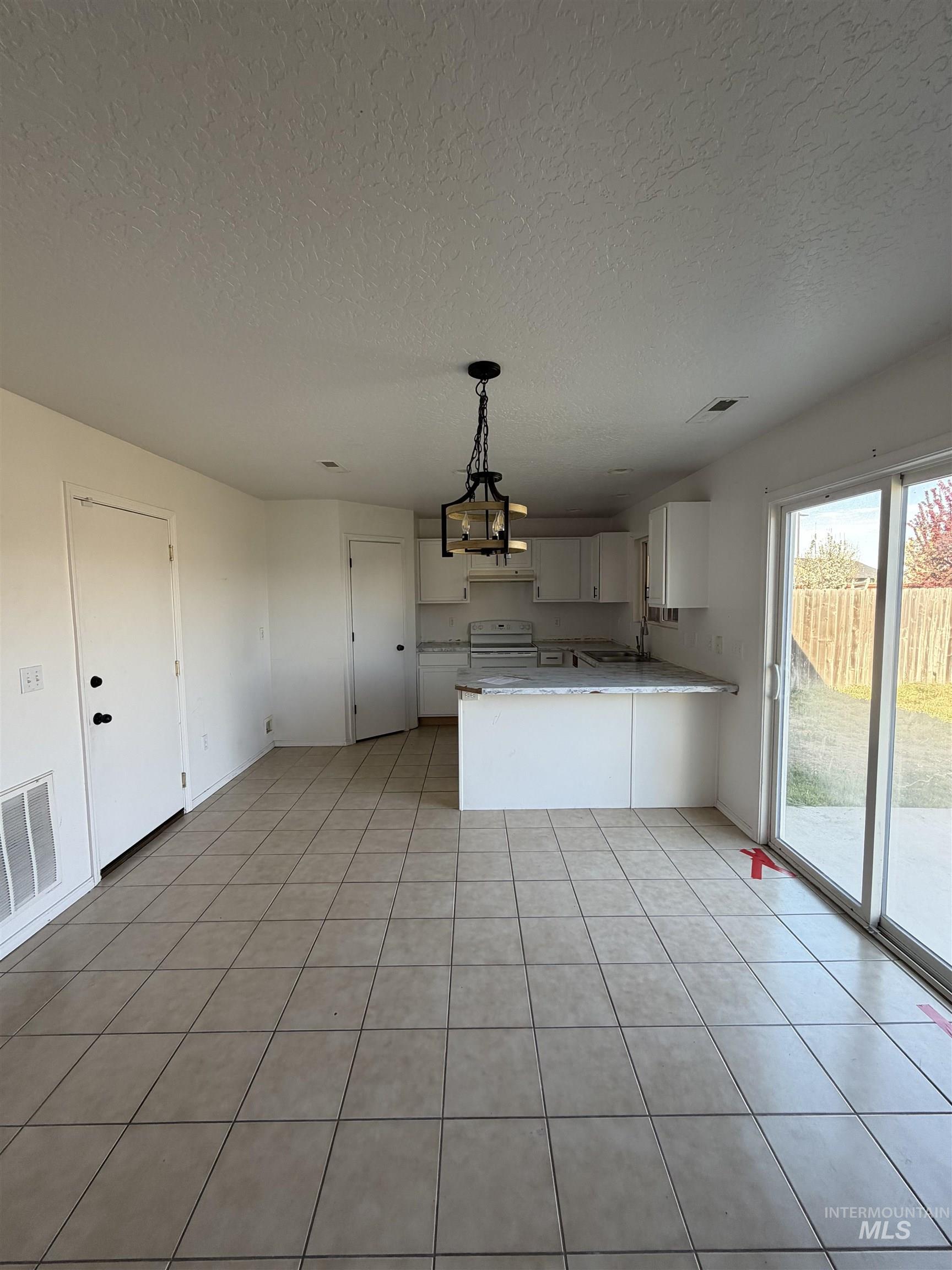 205 Middlepark Way Caldwell, ID 83605 - Photo 7 of 18 Kitchen with a peninsula, hanging light fixtures, electric range, a textured ceiling, and light tile patterned flooring