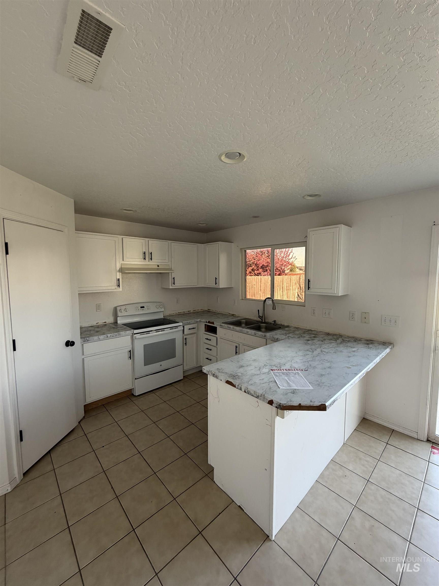 205 Middlepark Way Caldwell, ID 83605 - Photo 8 of 18 Kitchen with a peninsula, white electric range, white cabinetry, light countertops, and a kitchen bar