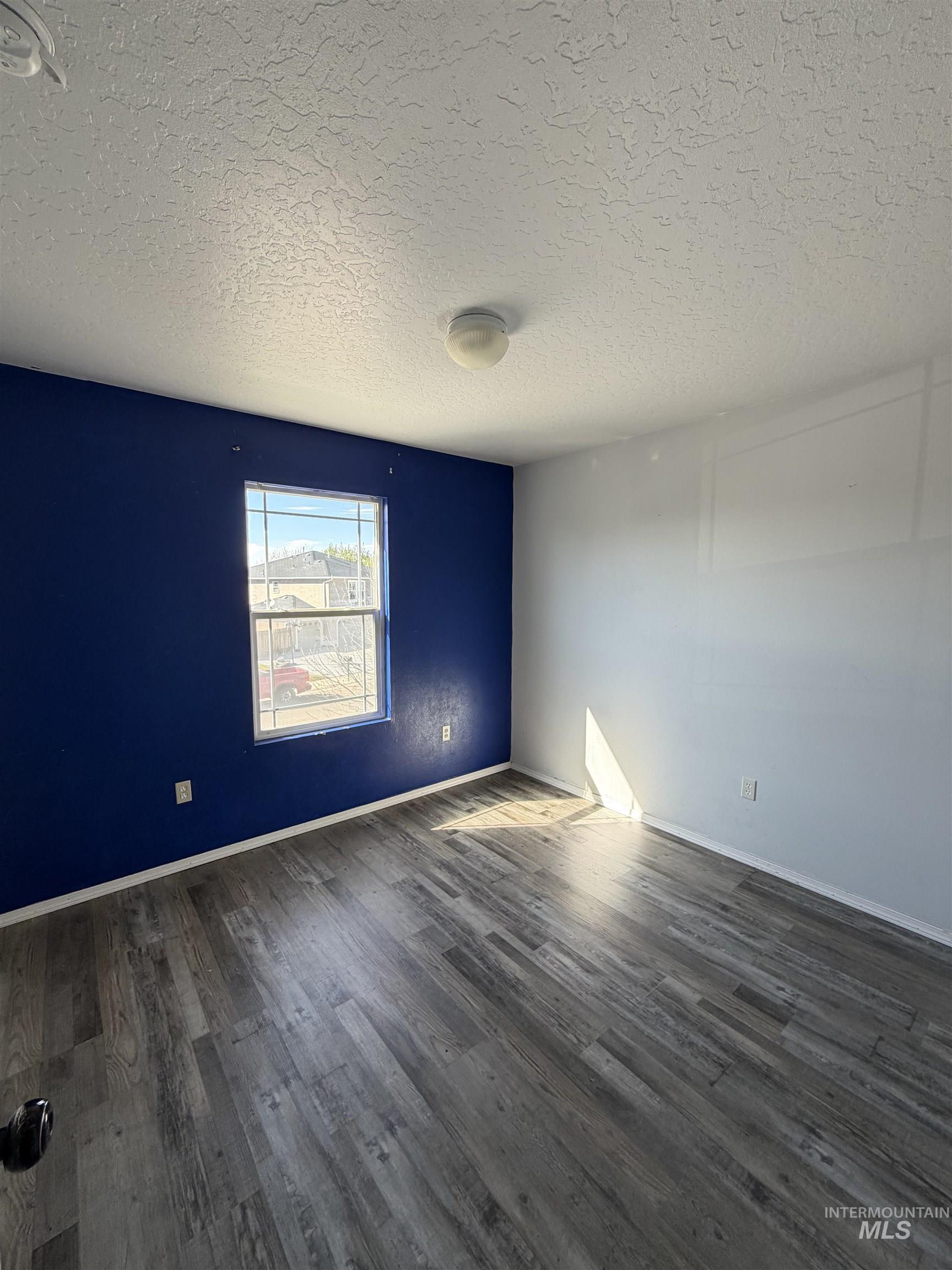 205 Middlepark Way Caldwell, ID 83605 - Photo 10 of 18 Empty room with dark wood-style flooring and a textured ceiling