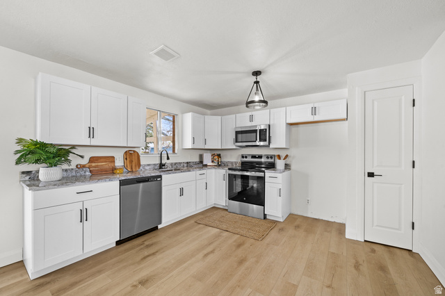2267 West 4350th Street South Roy, UT 84067 - Photo 11 of 32 Kitchen featuring stainless steel appliances, white cabinets, light wood finished floors, and light stone countertops
