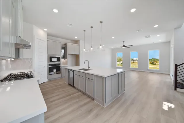 a large kitchen with stainless steel appliances kitchen island a large counter top and a wooden floors
