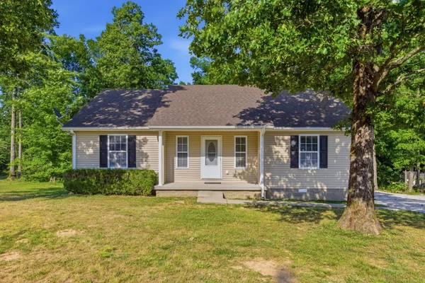 a front view of house with yard and trees in the background
