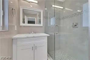 a bathroom with a granite countertop sink mirror and shower