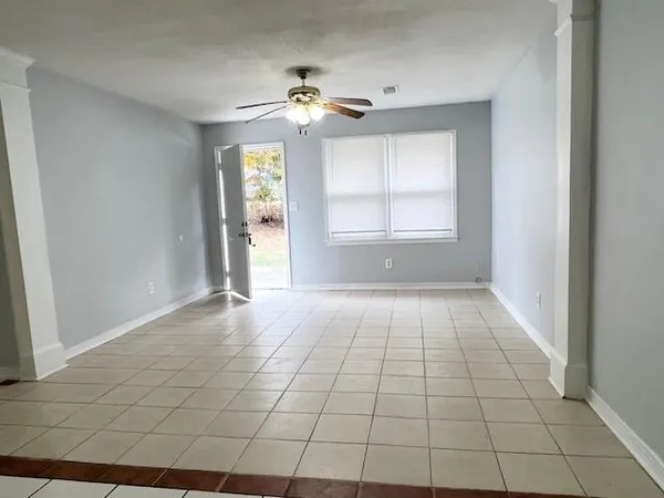 a view of an empty room with window and chandelier fan