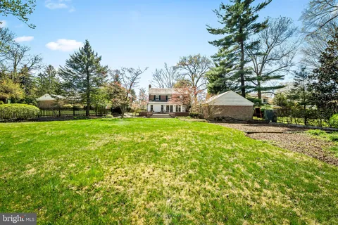 a view of a house with a big yard and large trees