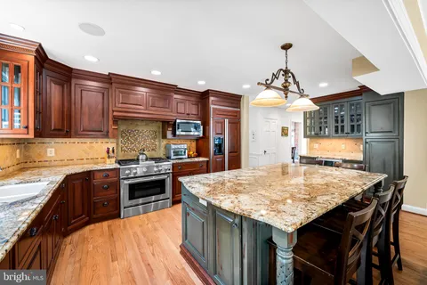 a kitchen with stainless steel appliances granite countertop wooden cabinets a stove a sink and a refrigerator