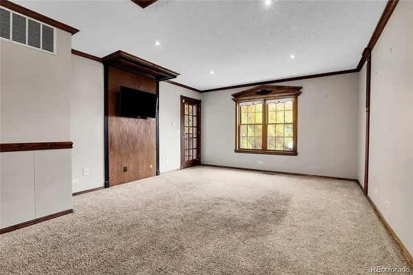 a view of an empty room with a window and a kitchen