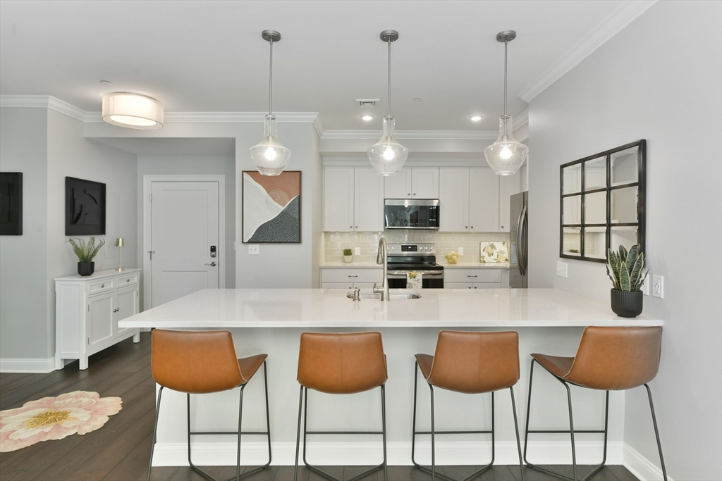 635 Old Post Road, Unit 2209 Sharon, MA 02067 - Photo 2 of 42 a kitchen with stainless steel appliances kitchen island granite countertop a table chairs and a view of living room