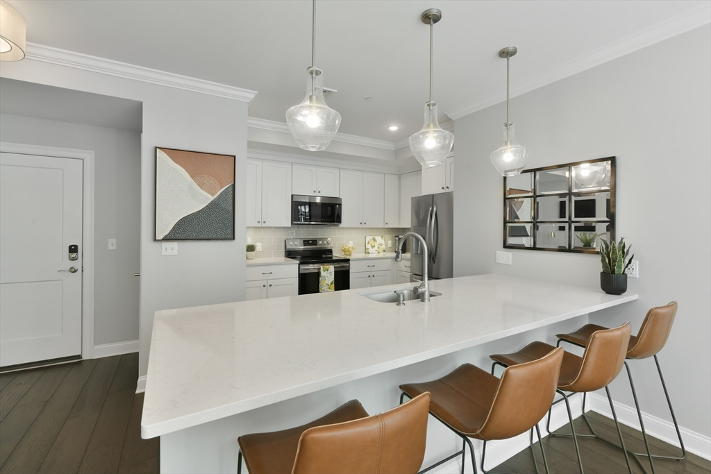 635 Old Post Road, Unit 2209 Sharon, MA 02067 - Photo 3 of 42 a kitchen with stainless steel appliances a dining table chairs refrigerator and microwave