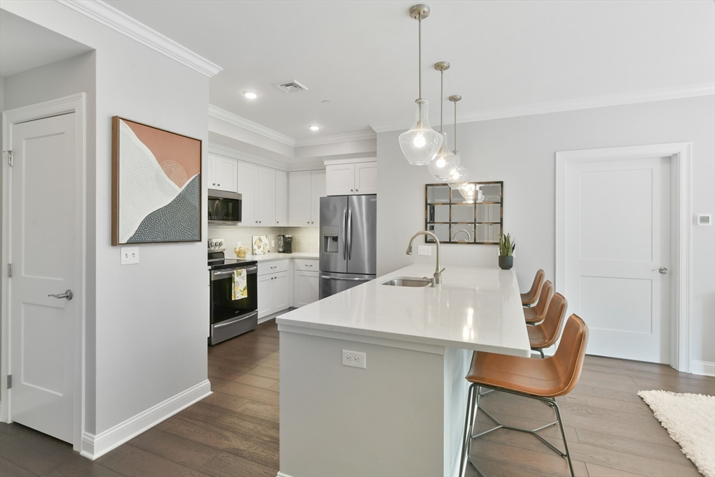 635 Old Post Road, Unit 2209 Sharon, MA 02067 - Photo 4 of 42 a kitchen with stainless steel appliances kitchen island a refrigerator and a dining table
