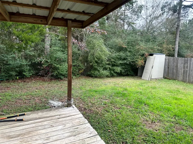 a view of a backyard with plants and large trees
