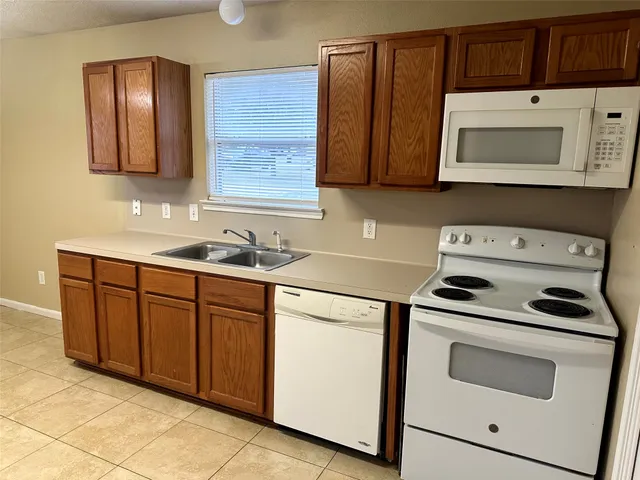 a kitchen with granite countertop a sink a stove and cabinets