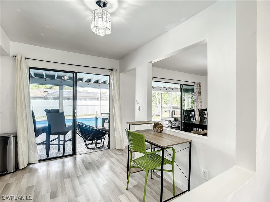 2437 42nd Terrace Southwest Naples, FL 34116 - Photo 11 of 34 a dining room with wooden floor a chandelier a glass table and chairs