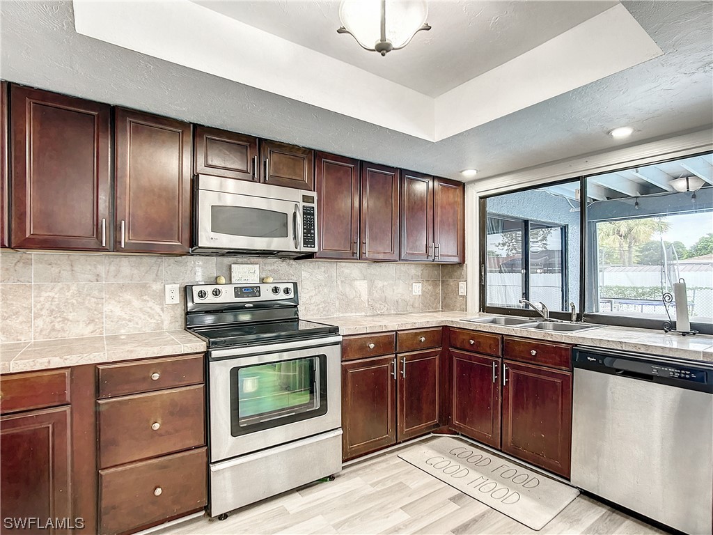 2437 42nd Terrace Southwest Naples, FL 34116 - Photo 12 of 34 a kitchen with stainless steel appliances granite countertop wooden cabinets and a stove top oven