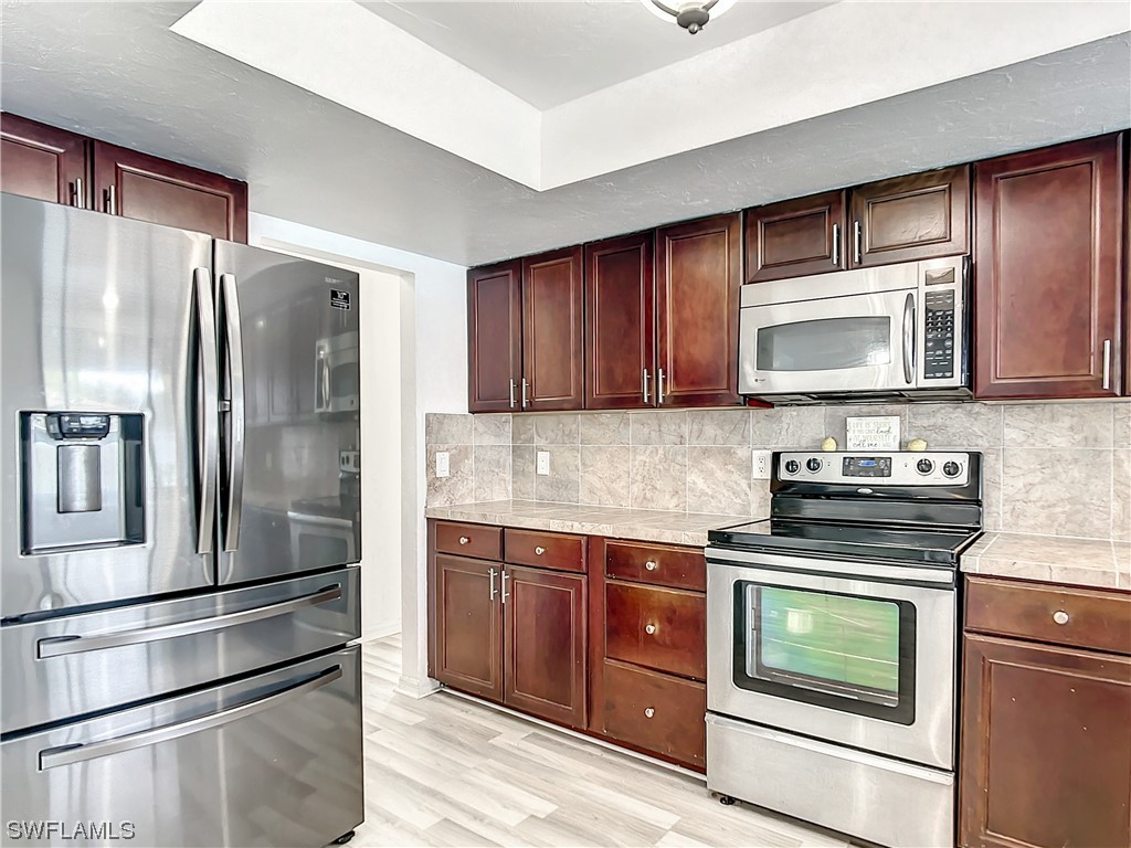 2437 42nd Terrace Southwest Naples, FL 34116 - Photo 14 of 34 a kitchen with stainless steel appliances granite countertop a refrigerator stove and sink