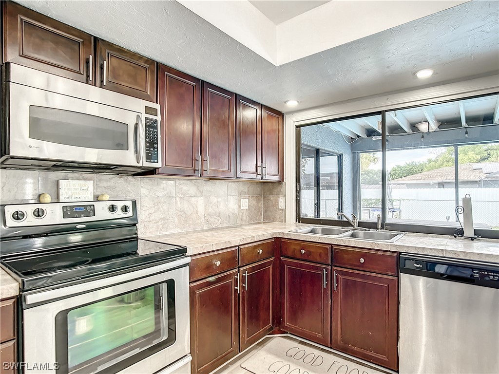 2437 42nd Terrace Southwest Naples, FL 34116 - Photo 15 of 34 a kitchen with stainless steel appliances wooden cabinets and a stove top oven