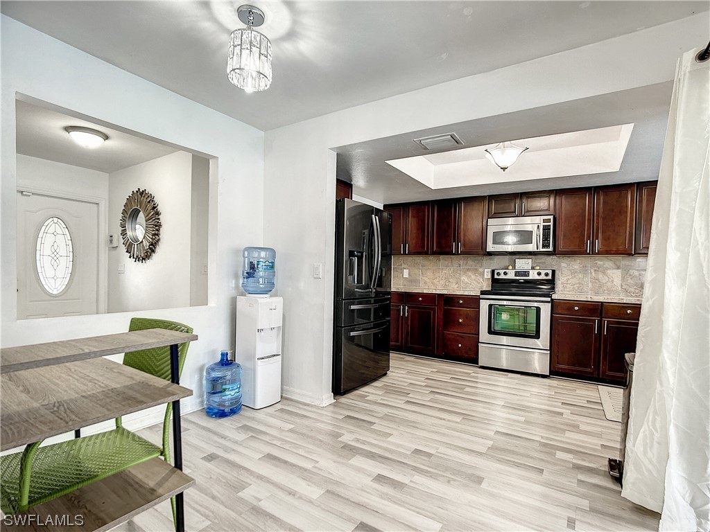 2437 42nd Terrace Southwest Naples, FL 34116 - Photo 16 of 34 a kitchen with stainless steel appliances granite countertop a refrigerator a sink dishwasher a stove with wooden cabinets and floor