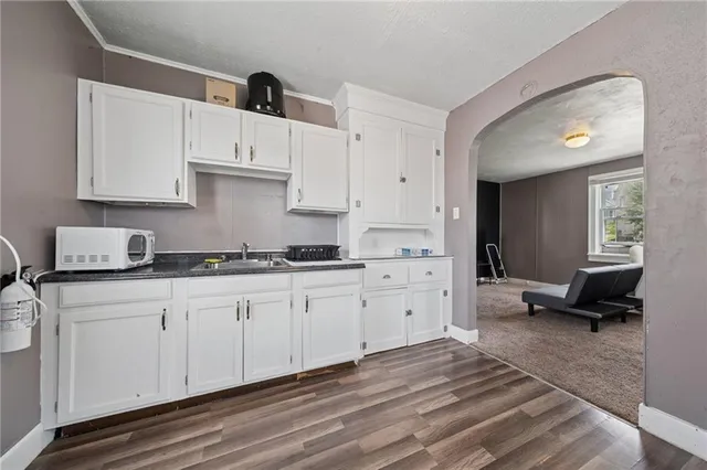 a large white kitchen with granite countertop a sink dishwasher a stove and a refrigerator with wooden floor