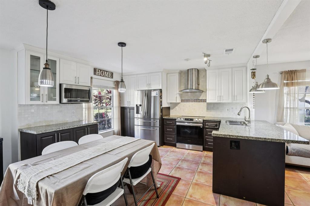 972 Azure Lane Weston, FL 33326 - Photo 4 of 61 a kitchen with stainless steel appliances kitchen island granite countertop a stove a sink a refrigerator a stove a kitchen island with a dining table and chairs