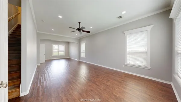 a view of an empty room with a window and wooden floor