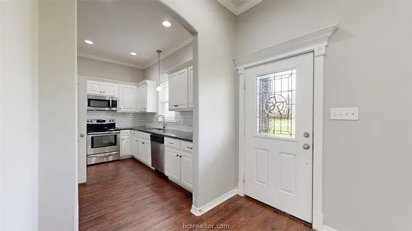 a kitchen with cabinets stainless steel appliances and wooden floor