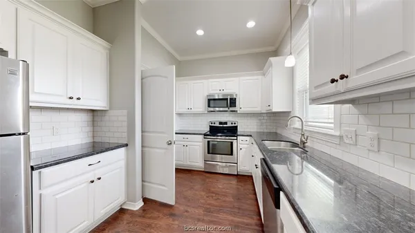 a kitchen with granite countertop white cabinets and stainless steel appliances