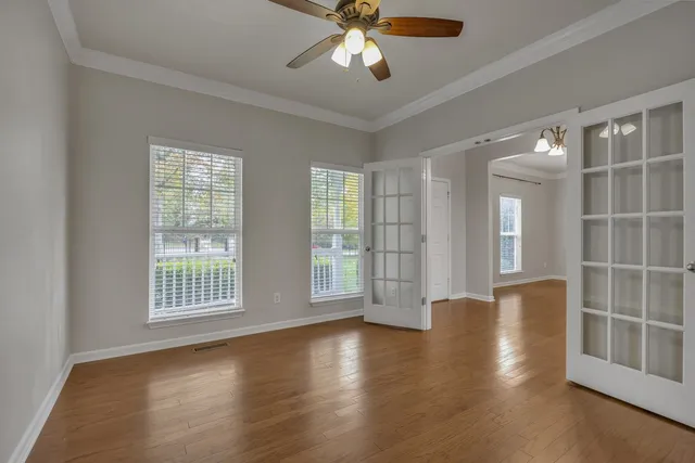 a view of an empty room with a window and wooden floor