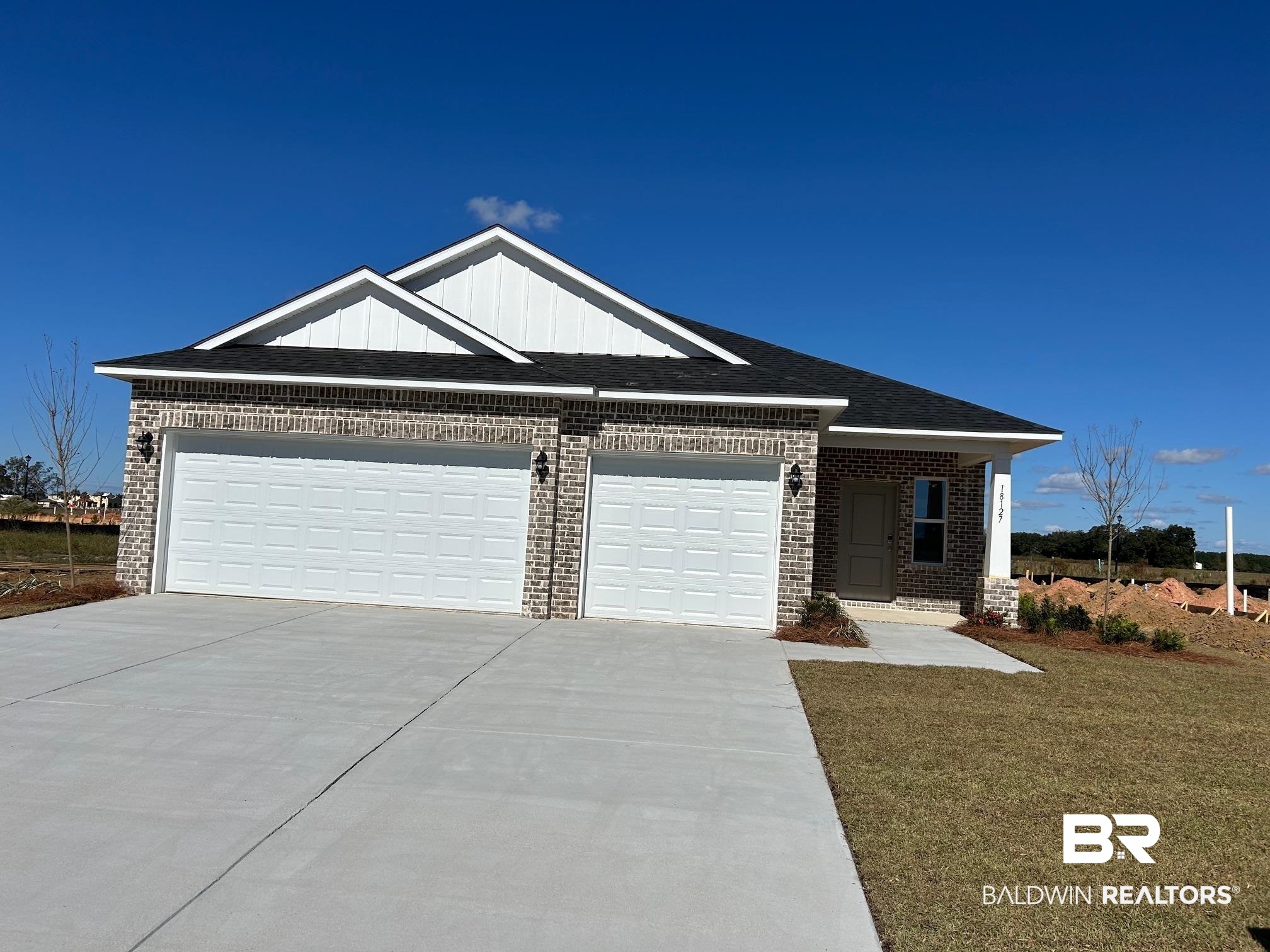 18127 Kent Circle Foley, AL 36535 - Photo 1 of 8 Ranch-style home featuring driveway, brick siding, a garage, board and batten siding, and a front lawn