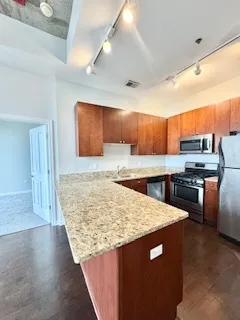 a kitchen with stainless steel appliances kitchen island granite countertop a table chairs and a refrigerator