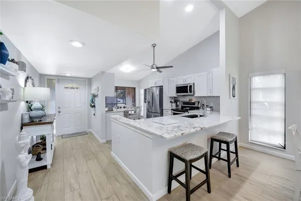 a kitchen with stainless steel appliances kitchen island granite countertop a refrigerator a stove a microwave oven a sink with island chairs and wooden floor