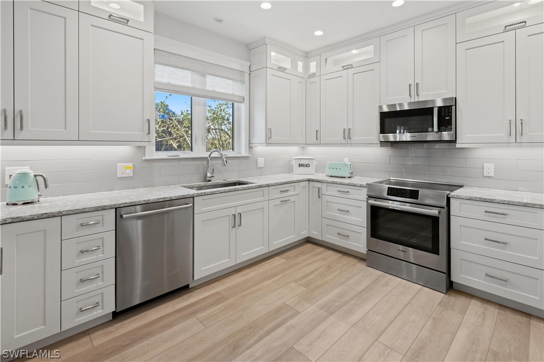 5294 Umbrella Pool Road Sanibel, FL 33957 - Photo 14 of 44 a kitchen with granite countertop white cabinets white stainless steel appliances and sink