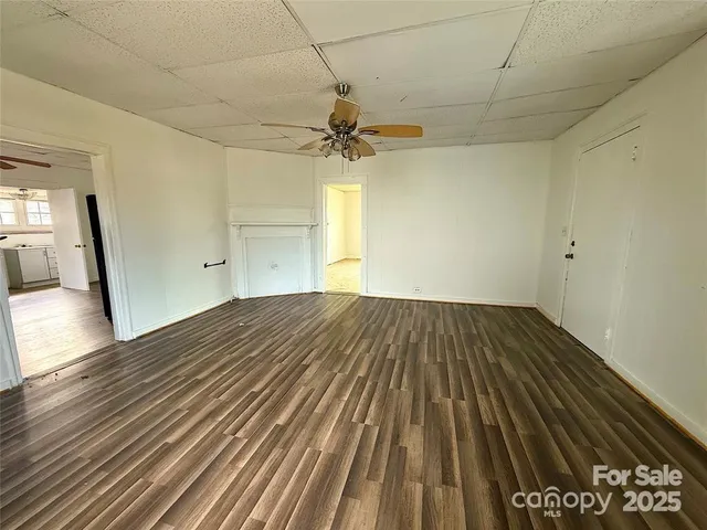 a view of a room with wooden floor a ceiling fan and staircase
