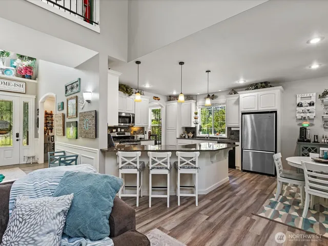 a kitchen with stainless steel appliances granite countertop a table chairs stove a refrigerator and cabinets