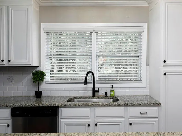 a kitchen with granite countertop white cabinets and a window