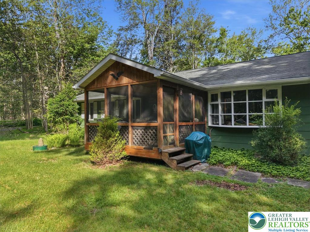 143 Logger Road Canadensis, PA 18325 - Photo 2 of 32 A quaint screened porch provides a peaceful outdoor retreat, overlooking the lush yard and surrounding trees.