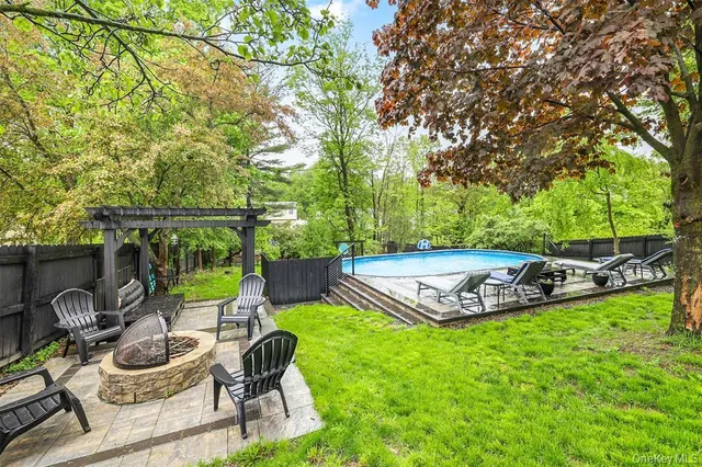 a view of a swimming pool with lawn chairs and a fire pit