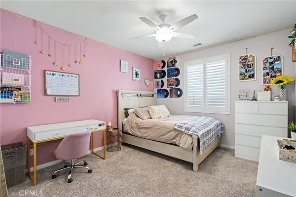 a bedroom with a bed a desk and chair with the walls