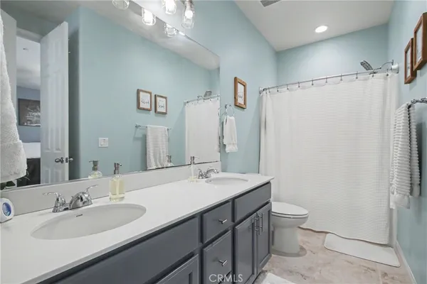 a bathroom with a double vanity sink toilet mirror and shower