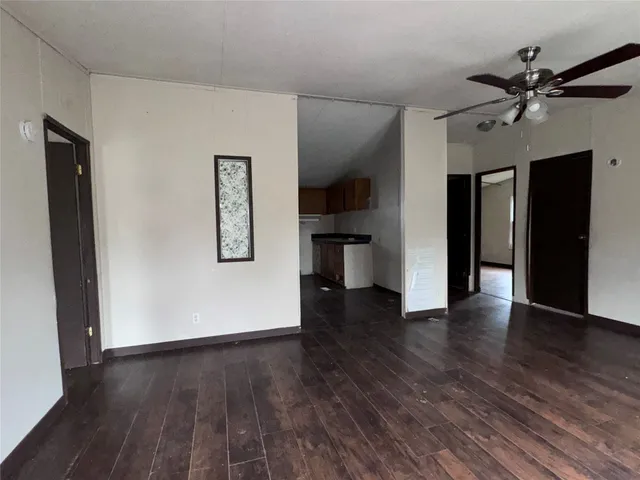 an empty room with wooden floor closet and windows