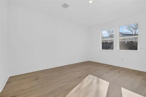 an empty room with wooden floor mirror and entrance