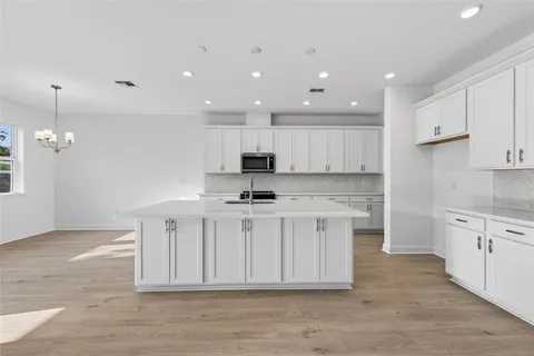 a kitchen with stainless steel appliances granite countertop a stove a sink a refrigerator and white cabinets